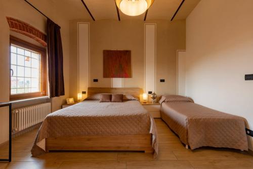 a bedroom with two beds and a window at Amaranto Bed & Breakfast in Cavour