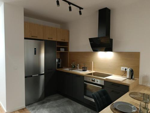 a kitchen with a stainless steel refrigerator and wooden cabinets at MODERN APARTAMENT Walendów in Walendów