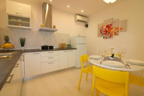 a kitchen with a dining table and yellow chairs at Melisa 5 in Poreč