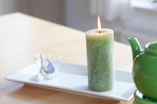 a green candle on a plate with a glass at Ferienhaus Innenförde in Holnishof
