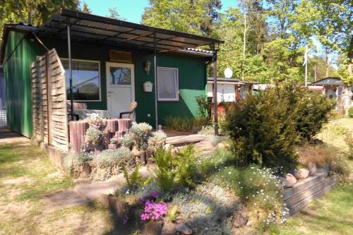 a green house with a garden in front of it at Ferienbungalow Fleesensee in Malchow