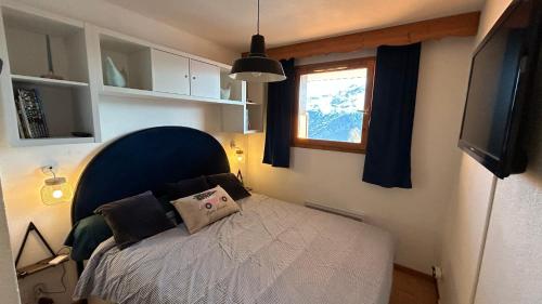 - une chambre avec un lit doté d'une tête de lit bleue et d'une fenêtre dans l'établissement Charming Apartment with a View, à Puy-Saint-Vincent