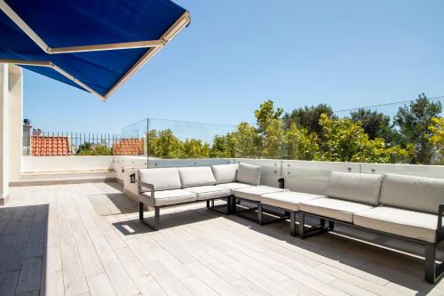 a patio with white couches and a blue umbrella at Cascais Duplex Apartment in Cascais