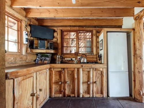 a kitchen with wooden cabinets and a white refrigerator at Mountain Canadian Log Home in Kalkheuvel