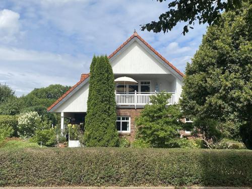 a white house with a white balcony and trees at MeerZeit hoch2 in Langballig