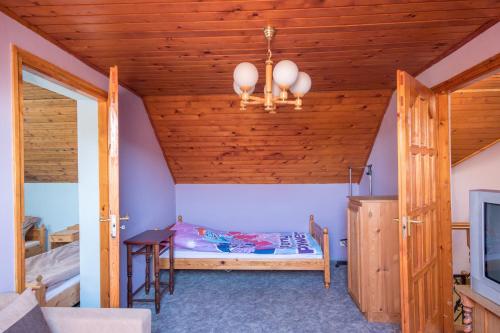 a small room with a bed and a wooden ceiling at Napsugár Vendégház in Poroszló