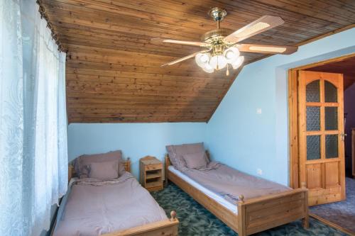 two beds in a room with a ceiling fan at Napsugár Vendégház in Poroszló