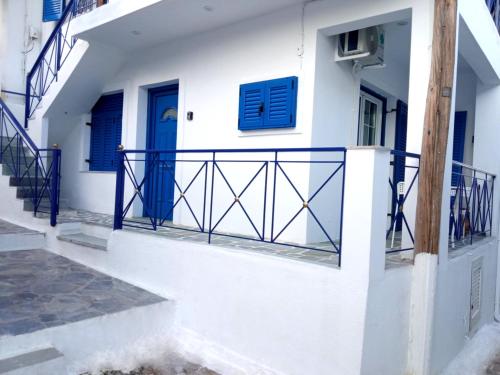a white house with blue doors and a balcony at Kea's Living Yard II in Korissia