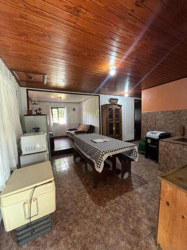 a living room with a table and a kitchen at Casa Tangerina - Lago Pinhal in Rio dos Cedros