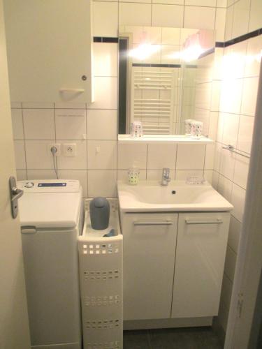 - une petite salle de bains blanche avec lavabo et miroir dans l'établissement Appartement Centre de CAUTERETS, à Cauterets