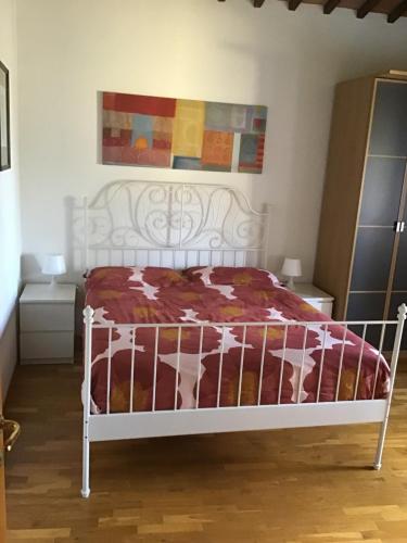a white bed with a red and white comforter at La Loggia del Ciliegio in Montespertoli