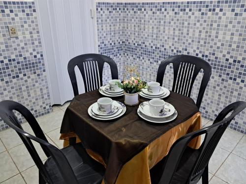 a table with black chairs and a table with cups and saucers at Apto H com cozinha em Macapa in Macapá