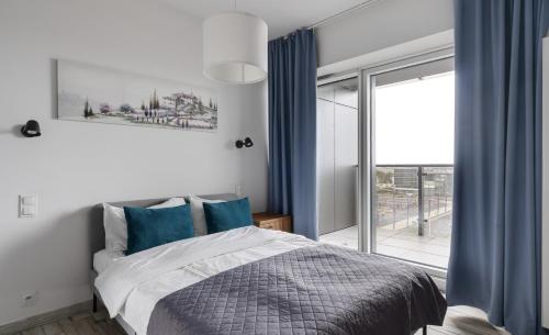 a bedroom with a bed with blue curtains and a window at Poznań Apartments Towarowa in Poznań