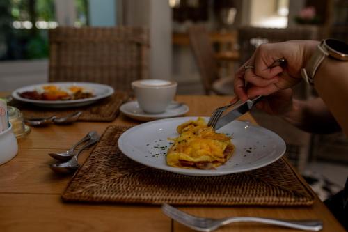 a person eating a plate of food with a fork and knife at Maison d'Ail Guest House in Franschhoek