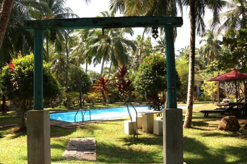 a swimming pool with a green archway next to a yard at Kurumba Villas in Bentota