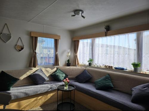 a couch in a living room with a large window at Buxton's Holiday Home - 'Park Holiday's' complex - St Osyth - Clacton-on-Sea in Saint Osyth