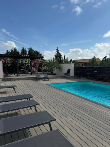 une piscine avec bancs et une terrasse en bois dans l'établissement 119 Sous le ciel de Provence - Aix, à Éguilles