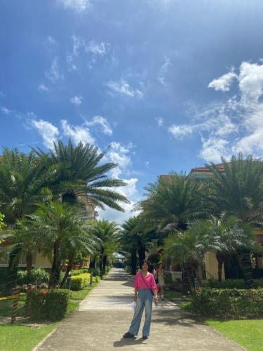 a woman walking down a sidewalk with palm trees at Sanremo Oasis, City de Mare in Cebu City