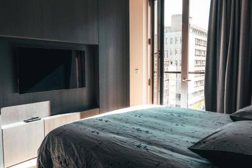 a bedroom with a bed and a tv and a window at Luxe City - Modern & Spacious 2BR with Balcony View in Luxembourg