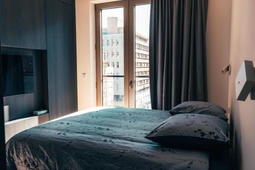 a bedroom with a bed and a large window at Luxe City - Modern & Spacious 2BR with Balcony View in Luxembourg