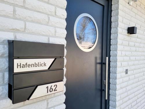a black door with a sign on a brick wall at WellnessOase Hafenblick in Walchum