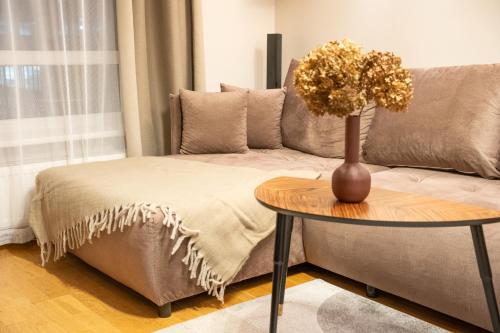 a living room with a couch and a table with a vase on it at Hygge Oasis for family with free parking and wi fi in Vilnius