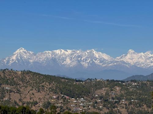 a mountain range with snow covered mountains in the background at Shantiniketan Mountain Home in Almora