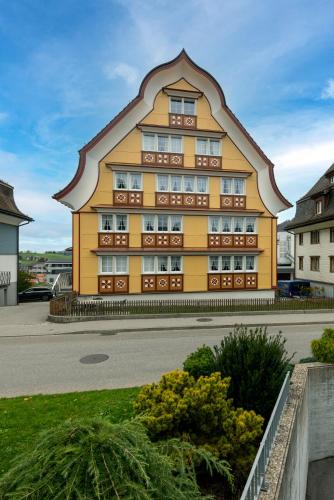 a large yellow building with a pointed roof at Blattenheimat - im traditionellen Appenzeller Haus in Appenzell
