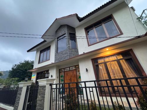 a white house with brown doors and a fence at Villa Munjul Indah - Majalengka in Jatipamor