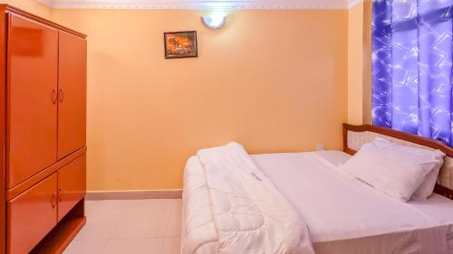 a small bedroom with a bed and a cabinet at Durban Hotel in Dar es Salaam