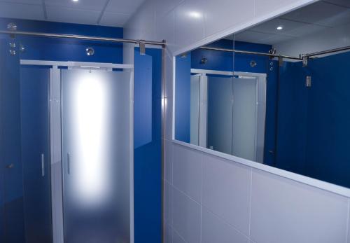 a bathroom with blue walls and a glass door at Albergue Alfonso II in Melide