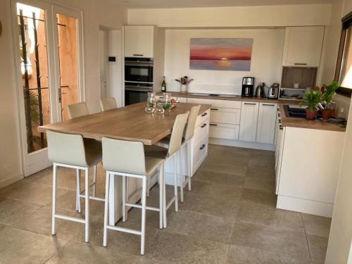 une cuisine avec une table en bois et des armoires blanches dans l'établissement La Bastide de Valcros - logement entier, à La Londe-les-Maures