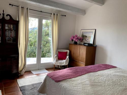 une chambre avec un lit, une fenêtre et une chaise dans l'établissement La Bastide de Valcros - logement entier, à La Londe-les-Maures