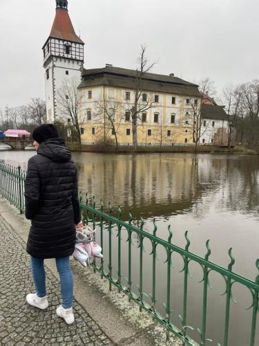 a woman standing next to a fence in front of a building at Apartmány Naxarův dvůr in Horažďovice