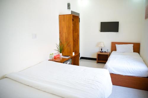 a hotel room with two beds and a television at Gold Stone Hoi An Homestay in Hoi An