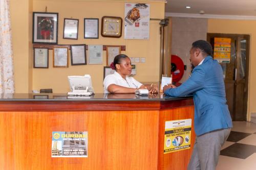 a woman standing at a counter talking to a dispatcher at Durban Hotel in Dar es Salaam