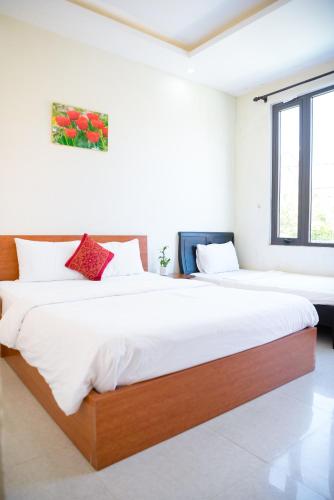 two beds in a room with white walls and windows at Gold Stone Hoi An Homestay in Hoi An