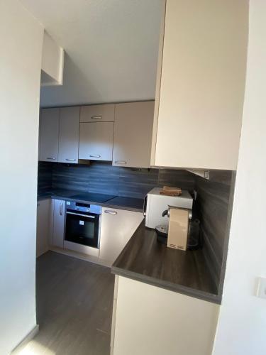 une cuisine avec des armoires blanches et un micro-ondes dans l'établissement Joli 2 pièces parc piscine vue mer, à Vence