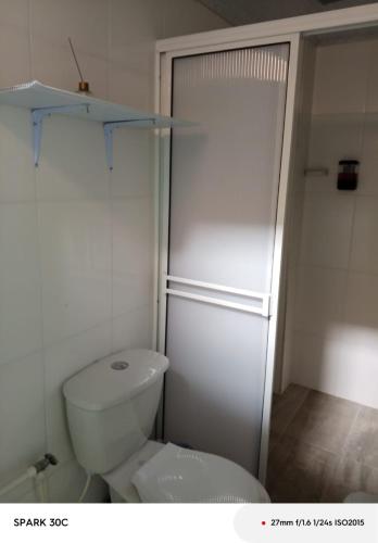 a white bathroom with a toilet and a shower at KOKOA GARDEN INN in San Vicente de Chucurí