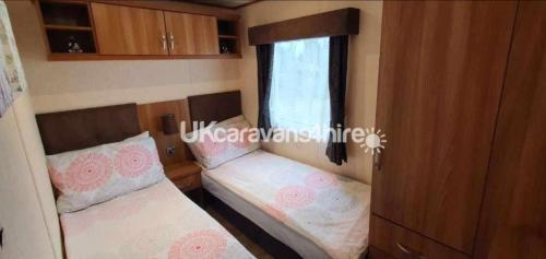 two beds in a small room with a window at Sunset 2 Static Caravan - Skegness in Winthorpe