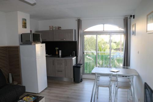 Il comprend une cuisine équipée d'un réfrigérateur blanc et d'une table avec des chaises. dans l'établissement Apt 4 couchages proche plage dans residence, au Cap d'Agde