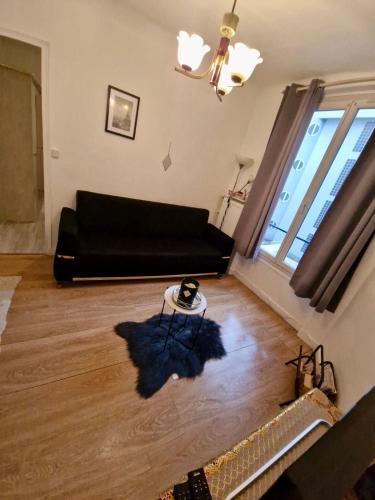 un salon avec un canapé noir et une table dans l'établissement Logement 2 pièces très bien situé, proche parc des princes, à Boulogne-Billancourt