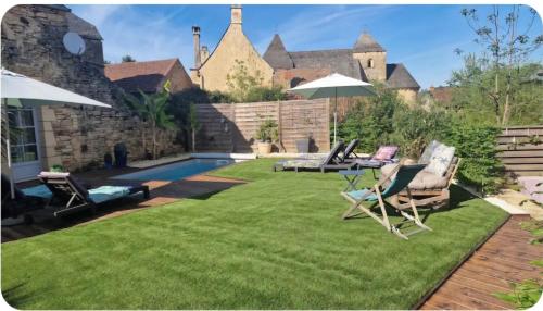 une personne assise à une table avec un ordinateur portable sur une pelouse dans l'établissement La Grange Périgord - Sarlat - Piscine privée, à Archignac