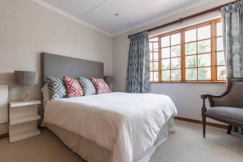 um quarto com uma cama, uma cadeira e uma janela em Sandown Estate Apartment em Joanesburgo