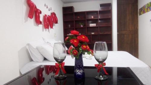 two wine glasses and a vase with flowers on a table at KOKOA GARDEN INN in San Vicente de Chucurí