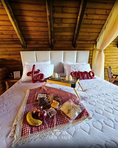 a bed with a tray of food on it at Chalé Araucária in Bom Retiro