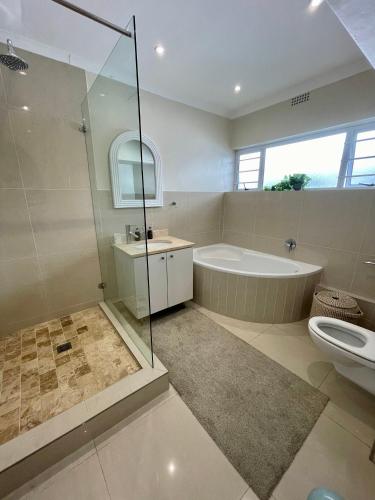 a bathroom with a shower and a tub and a toilet at Ideal location, Mouille Point in Cape Town