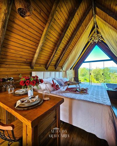 a bedroom with a bed and a table with flowers on it at Chalé Araucária in Bom Retiro