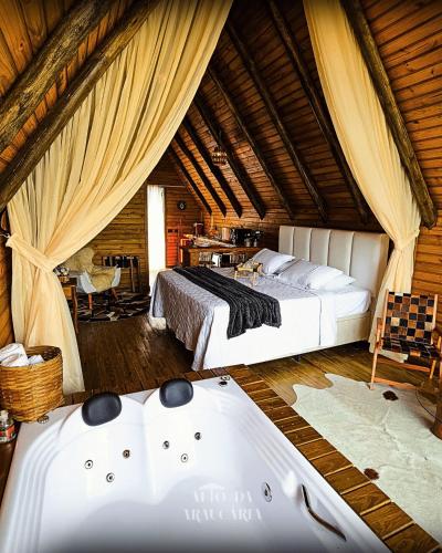 a bedroom with two beds and a tub in a room at Chalé Araucária in Bom Retiro