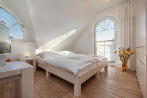 a white bedroom with a bed and two windows at Godeke Michels Ferienwohnung 23-Jonggöntje Seestr5b in Groß Kirr